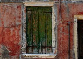 Rustic green shutter on weathered red wall with rustic textures photo