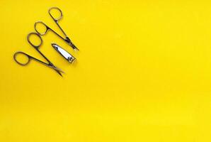 Metal scissors and nippers on a yellow background, space for text. Manicure, pedicure concept. photo