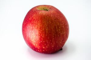 Fresh red apple sits on a white surface, showcasing its vibrant color and smooth texture in natural light photo