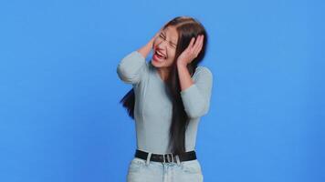 Don't want to hear and listen. Frustrated annoyed irritated woman covering ears gesturing No, avoiding advice ignoring unpleasant noise loud voices. Brunette girl isolated alone on blue background video
