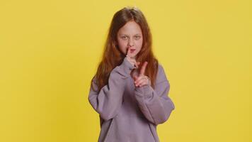 Shh be quiet please. Preteen child girl kid presses index finger to lips makes silence hush gesture sign do not tells gossip secret. Little cute children isolated alone on studio yellow background video
