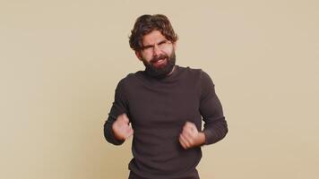 Lebanese young man in long sleeves screams yell from stress tension problems feels horror hopelessness fear panic surprise shock expresses gestures rage. Indian guy isolated on beige studio background video