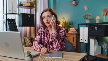 Young businesswoman freelancer answering to client on mobile phone call using smartphone. Conversation. Caucasian woman girl working online remote distance job, talking discussing at home office desk. video
