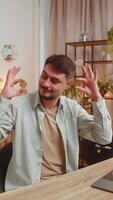 Young man freelancer stock trader earning holding showing bitcoins BTC after online monitoring trading operation. Increasing wealth financial prosperity. Guy with laptop at home office table. Vertical video