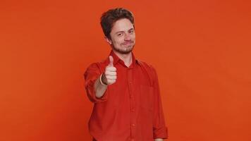 Like. Caucasian man raises thumbs up agrees with something or gives positive reply recommends advertisement likes good idea feedback celebrating success victory. Guy isolated on orange background video