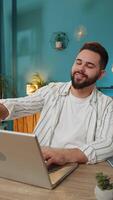 Happy Caucasian man closing laptop pc after finishing work. Guy freelancer working online, remote job at home office table workplace. E-learning, browsing internet on notebook computer. Vertical video