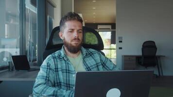 Office worker sitting at desk, looking away in thought while using laptop, brainstorming new ideas in modern, bright office, taking break from work to contemplate next steps video
