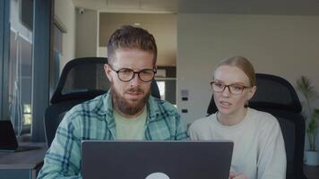Human resources specialist, man and woman, are attentively working together on laptop in bright, modern office, demonstrating teamwork and collaboration. Human resources specialist at work video