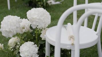An Elegant White Floral Decor Comprising Chairs Set in an Outdoor Setting Ideal for Events. Action video