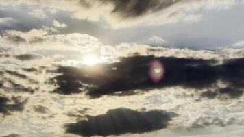 Sunlight breakig through cumulus cloud at sunset. Sun going down behind gray clouds on sky at summer day. Beautiful nature background. Close up Slow motion video
