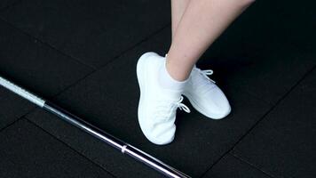 girl in white sneakers develops ankle Woman stretches ankle on treadmill closeup. Sportswoman performs leg warming-up before running on training machine. Proper sports preparation video