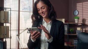 Happy Caucasian woman smiling holding using mobile phone smartphone cellphone female girl online gadget app manager businesswoman business worker employee in office entrepreneur social media internet video