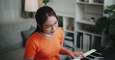 Handheld high angle view shot, A determined young woman is practicing her keyboard alone and enjoys a peaceful moment with music. Relaxing holiday at home video