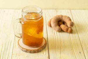 Delicious sweet drink tamarind juice and ice cube on wooden backgroud photo