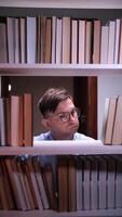 vertical bibliotecário procurando para livro em estante de livros dentro biblioteca video