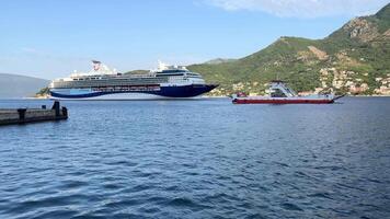 Bay of Kotor, Montenegro, June 20, 2025. A large cruise ship sails towards the ferry, creating a dynamic maritime scene surrounded by beautiful Mediterranean nature video