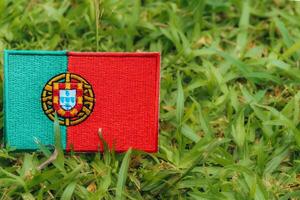 Horizontal eco friendly Portugal flag PT crafted from fabric and thread, placed on green grass in warm natural light. Symbol of climate change, Earth Day and environmental harmony. photo