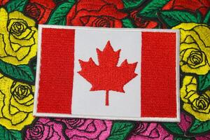 Eco friendly embroidered Canada flag placed on colorful handmade floral embroidery of roses, crafted from thread and fabric. Cultural and natural harmony. photo