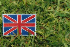 Horizontal eco friendly Union Jack flag, made from fabric and thread, placed on green grass under warm light in Europe. Symbolizing climate change, Earth Day and environmental harmony. photo