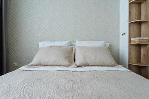 In a cozy bedroom, there sits a bed adorned with a warm blanket and several plush pillows, positioned adjacent to an inviting bookshelf filled with various books and decorative items photo