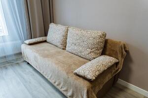 In a cozy living room, a brown couch is gracefully placed next to a window, creating a warm and inviting atmosphere for relaxation and enjoyment of natural light coming through photo