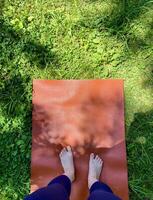 A person standing on a yoga mat in the grass photo