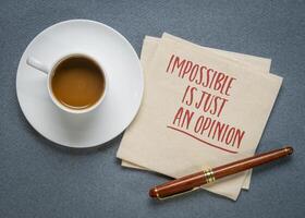 Impossible is just an opinion - inspirational writing on a napkin with coffee photo