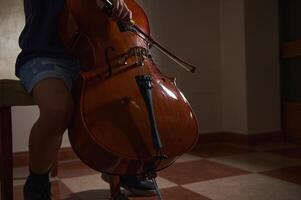 A person engaged in a musical performance, seated and playing a cello. The scene captures intimacy and passion for music in a serene environment. photo
