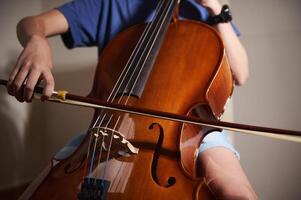 Close-up image of a person playing the cello, showcasing musical precision and artistic expression, set in a music studio environment. photo