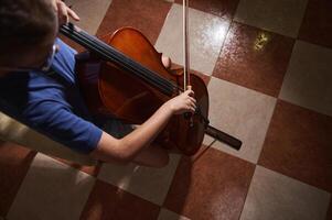 Close-Up of a Cellist Playing a Cello on Checkered Flooring in Evening Light photo