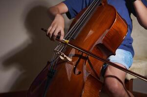 An image capturing the hands of a cellist gripping a bow and playing a cello. The lighting highlights the instrument's polished wood, symbolizing musical passion and creativity. photo