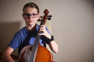 Young Musician Playing a Cello in a Dramatic Indoor Setting photo