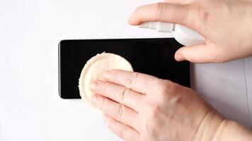 Cleaning smartphone screen with spray and cloth. stepbystep demonstration. video