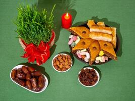 A traditional Navruz table. The day of the vernal equinox. Wheat sprouts, Arab dessert baklava, sweets, nuts, dried fruits on a table covered with a tablecloth. photo