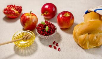 Rosh Hashanah, the Jewish New Year. Traditional symbols are tallit, apples, pomegranate, hala bread and honey on a light background. Happy Rosh Hashanah. Shana Tova photo
