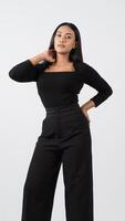Elegant fashion model in a chic black outfit poses confidently in a studio.. photo