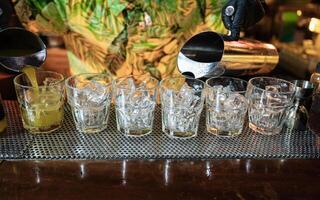 Bartender pouring Cocktail fruits in glass with ice on counter photo