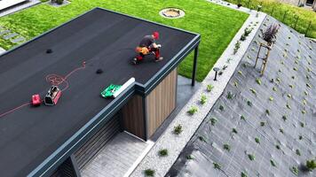 Roofer Performing EPDM Roof Maintenance While Using Guitar for Entertainment at Modern Carport video
