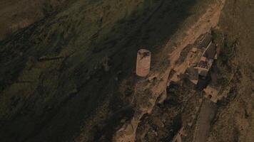 Caucasus cave monastery nestled on isolated mountain slope with ancient tower and cliff side dwellings at dusk, symbolizing solitude, heritage, and spiritual retreat video