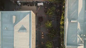 Tbilisi, Georgia - 1st july, 2025 -Aerial Fabrika courtyard in Tbilisi, vibrant social hub with outdoor seating, trees, string lights, groups of guests enjoying the lively atmosphere in heart of city video