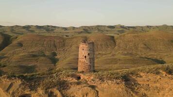 Aerial view of an ancient stone watchtower standing alone on a remote ridge in David Gareja, Georgia, symbolizing medieval defense, isolation, and border vigilance. video
