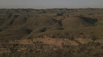 Scenic aerial view of rugged green hills with dramatic shadows and earthy textures at sunset video
