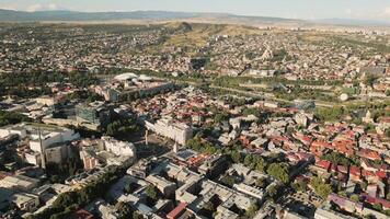 Aerial panoramic view of Tbilisi Georgia showing cityscape with Sameba Cathedral, Rike Park, Bridge of Peace, Presidential Palace, and central Freedom Square in warm daylight video