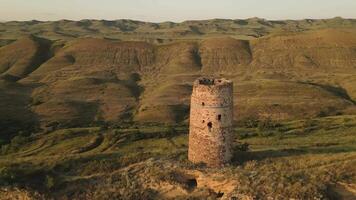 Aerial fly over view of an ancient stone watchtower standing alone on a remote ridge in David Gareja, Georgia, symbolizing medieval defense, isolation, and border vigilance. video