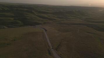 Aerial view serene rolling green hills with winding paths under soft warm sunset light video
