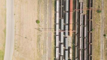 Drone shot directly above freight train yard showing cargo wagons on parallel tracks, symbolizing industrial logistics, export-import flow, and transportation infrastructure video