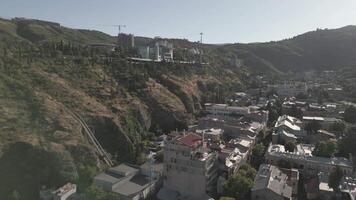 Aerial view of Tbilisi showing modern hilltop architecture and cable car above dense traditional residential area highlighting wealth contrast video