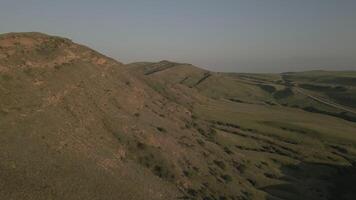 Aerial serene rolling green hills with winding paths under soft warm sunset light video