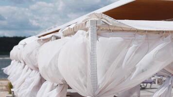 Close-up of white fabric on the shore. Gazebo on the beach. Storm, wind. video