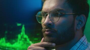 Confident programmer Arabian Indian man looking analyzing computer chart pc graph crypto currency bitcoin IT specialist freelancer male thinking ethnic guy broker trader neon office trading decision video